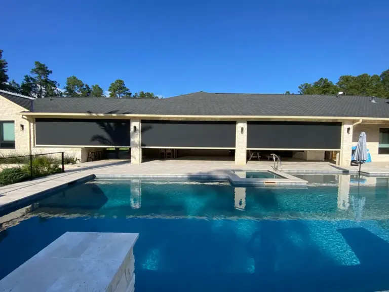 Ranch home with three motorized screens lowered across its covered patio behind a pool