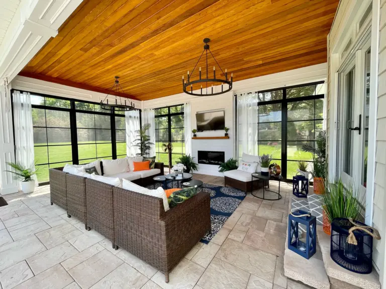 Three-season room with a cedar ceiling, chandelier, fireplace and large black-framed screened windows